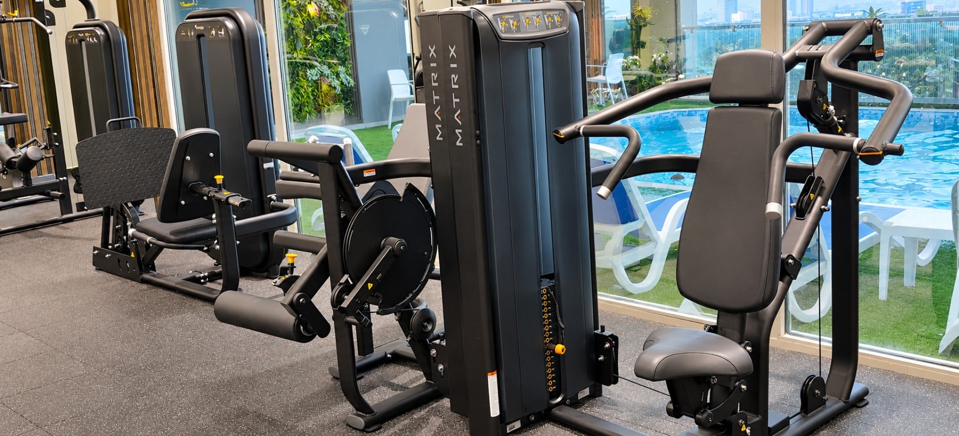 Strength-training machines overlooking the shared building pool