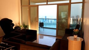 Un salon moderne doté d’une grande porte-fenêtre coulissante donnant sur un balcon avec vue sur la ville.