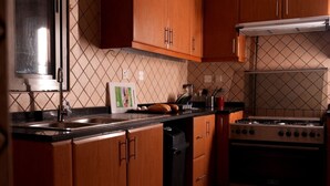 Une cuisine avec des meubles de rangement en bois, une cuisinière à gaz, un lave-vaisselle et un dosseret carrelé.