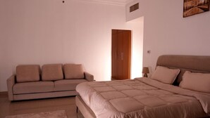 A bedroom with a bed, a sofa, a nightstand, and a door.