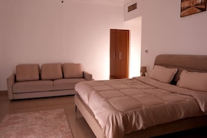 A bedroom with a bed, a sofa, a nightstand, and a door. - Deluxe Double Room with lake views near Dubai (Sharjah)