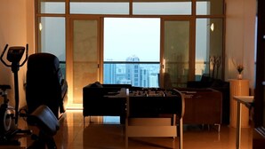 A spacious room with a foosball table, exercise bike, and a large window offering a city view.