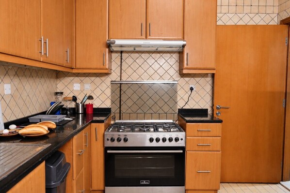 A kitchen with wooden cabinets, a gas stove, and a tiled backsplash.