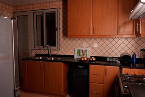 Une cuisine avec des meubles de rangement en bois, un lave-vaisselle, une cuisinière et un évier.