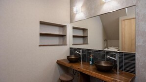 Un baño con tocador de madera, dos lavamanos, un espejo y un perchero para toallas.