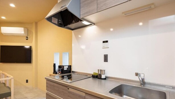 Una cocina moderna con estufa integrada, un lavamanos y un televisor de pantalla plana montado en la pared.