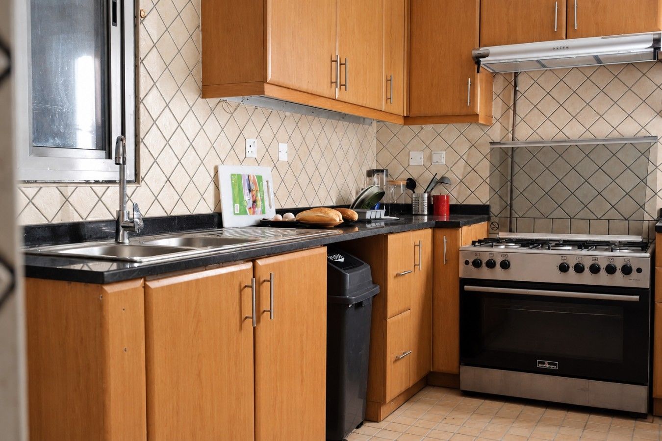 Une cuisine avec des meubles en bois, un évier en acier inoxydable, une cuisinière à gaz et un lave-vaisselle.