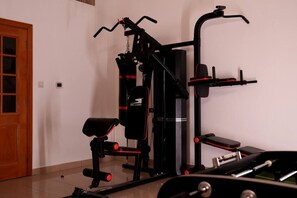 A home gym with a bench press, a pull-up bar, and a weight bench. - Double Room with Lake View near Dubai (Sharjah)