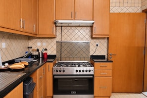 A kitchen with wooden cabinets, a gas stove, and a tiled backsplash.