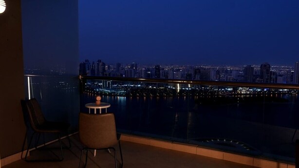 A balcony with a city view, a chair, and a small table.