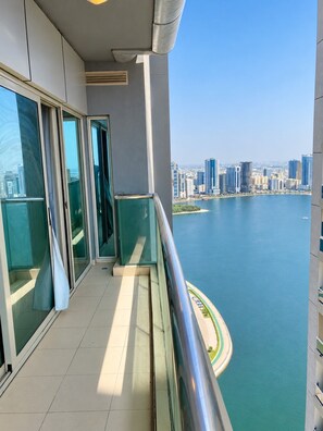 A balcony with a city view overlooking a body of water and high-rise buildings.