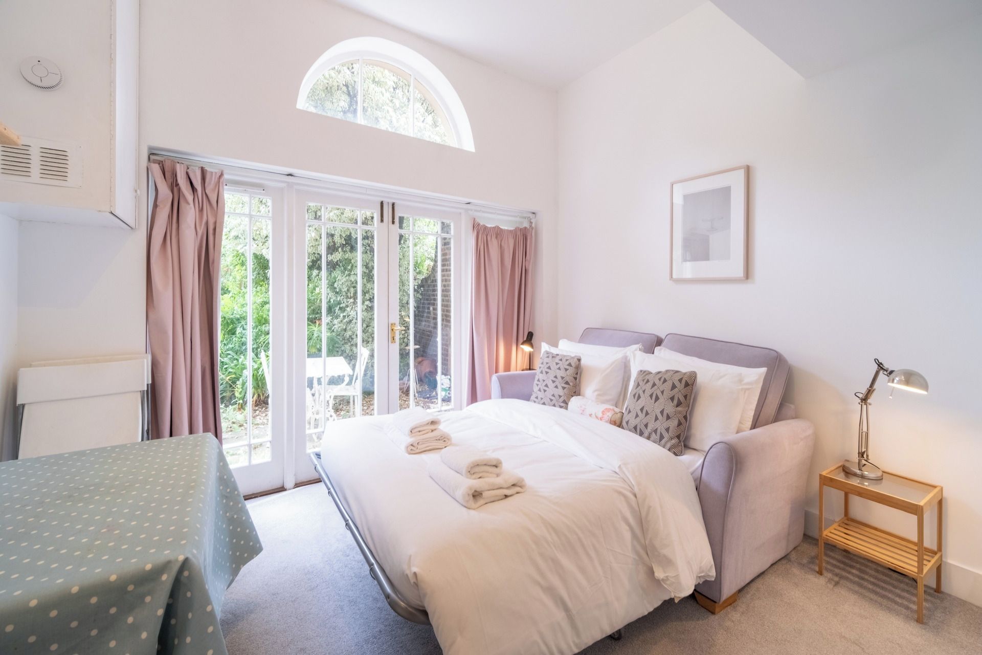 A bedroom with a bed, a bedside table, a lamp, and a window with curtains.