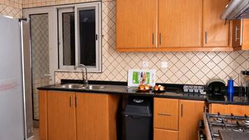 A compact kitchen with wooden cabinets, a stainless steel sink, a dishwasher, and a gas stove.