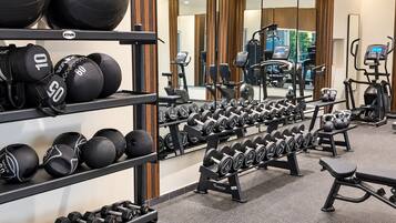 A gym with various exercise equipment including dumbbells, medicine balls, and treadmills.