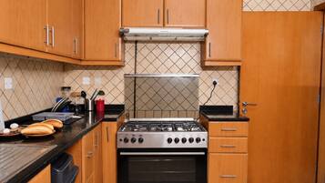 Una cocina con armarios de madera, estufa a gas y salpicadero de azulejos.
