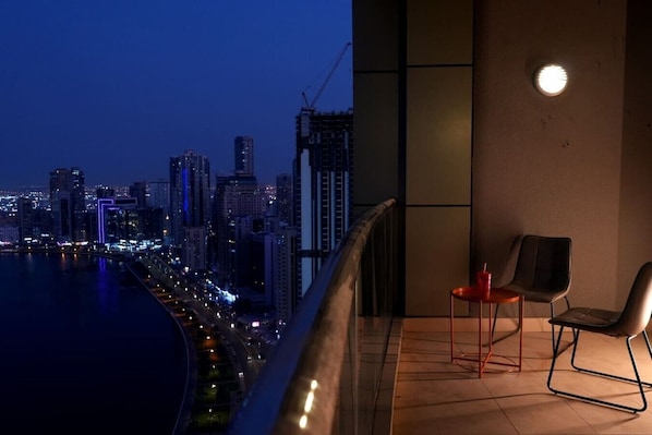 A balcony with a view of a cityscape at dusk, featuring modern buildings and a waterfront.