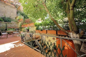 A courtyard with a wooden staircase, outdoor seating, and potted plants. - Vatican Luxury Apt with Garden (Roma)