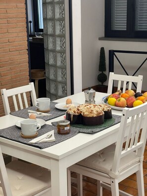 A dining table with white chairs, a cake, fruit, and condiments. - Vatican Luxury Apt with Garden (Roma)