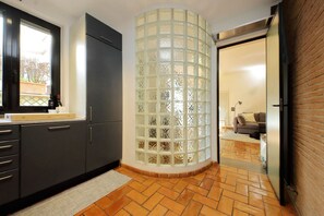 A kitchen with dark cabinets, a window, a glass partition, and a tiled floor. - Vatican Luxury Apt with Garden (Roma)