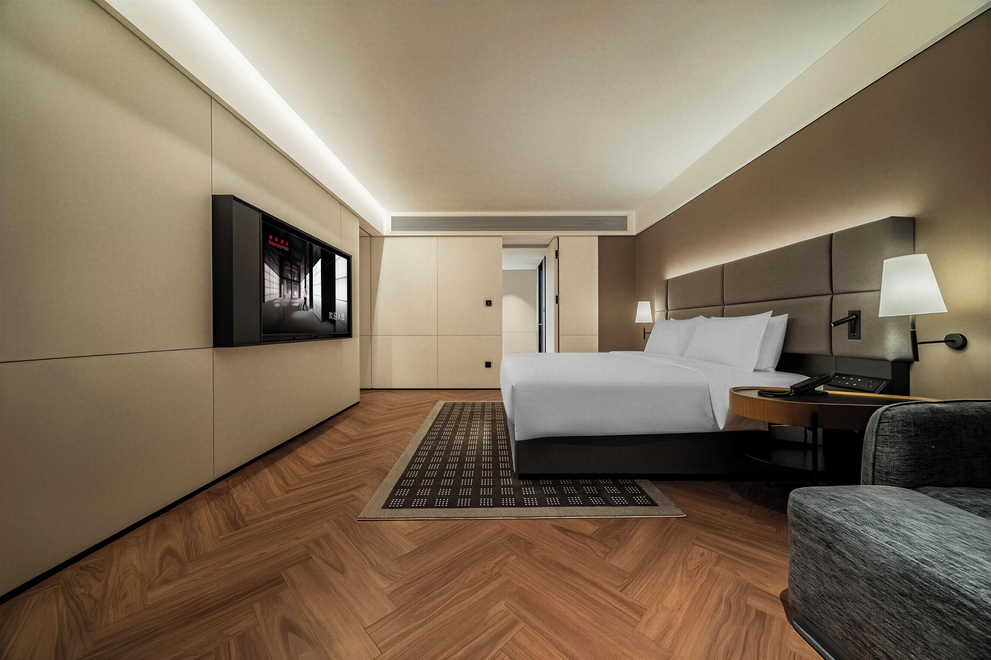 Una habitación de hotel con cama, mesita de noche, lámpara y televisor montado en la pared.