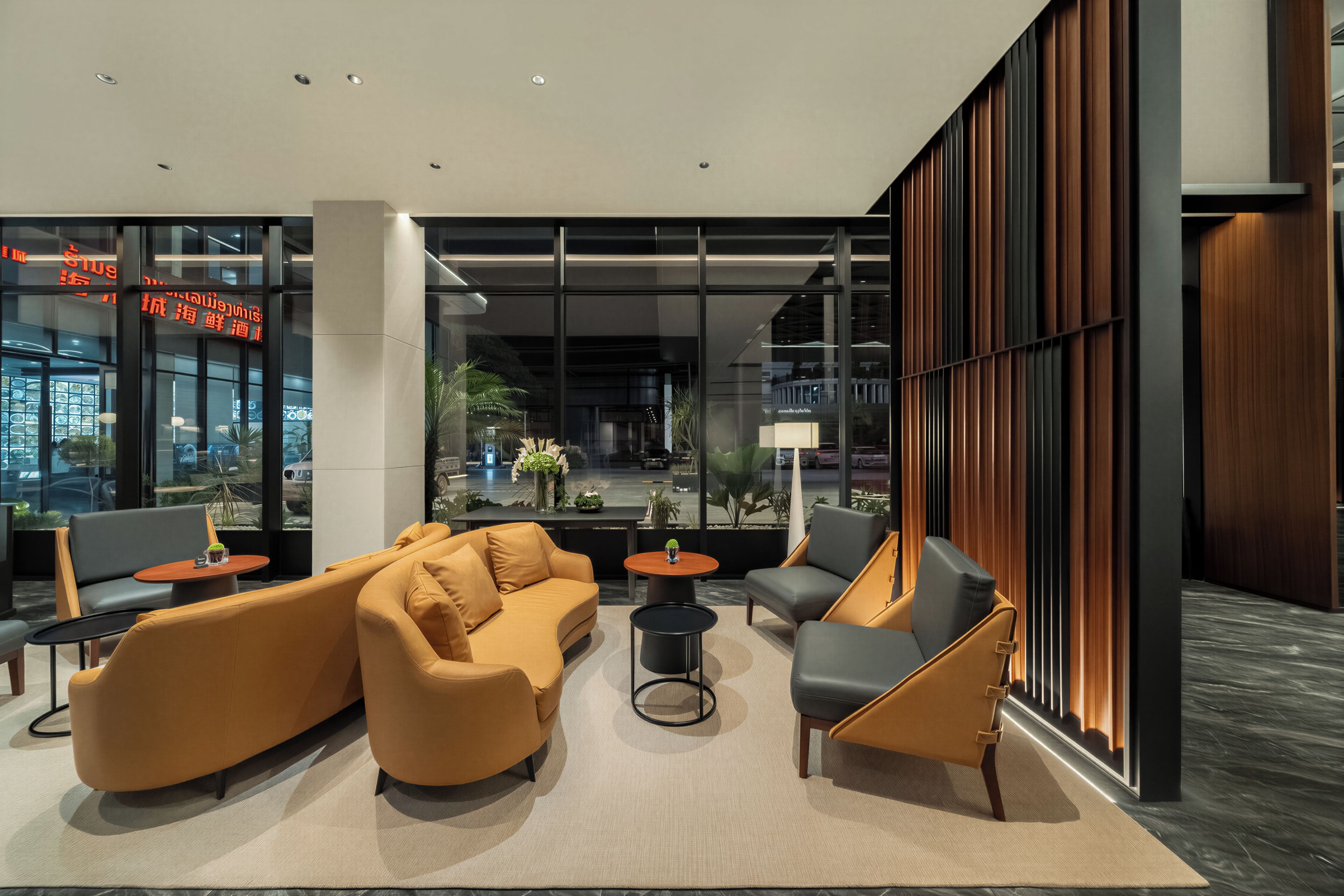 A modern lobby with seating arrangements, large windows, and a view of the street.