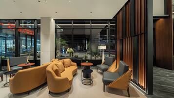 A modern lobby with seating arrangements, large windows, and a view of the street.