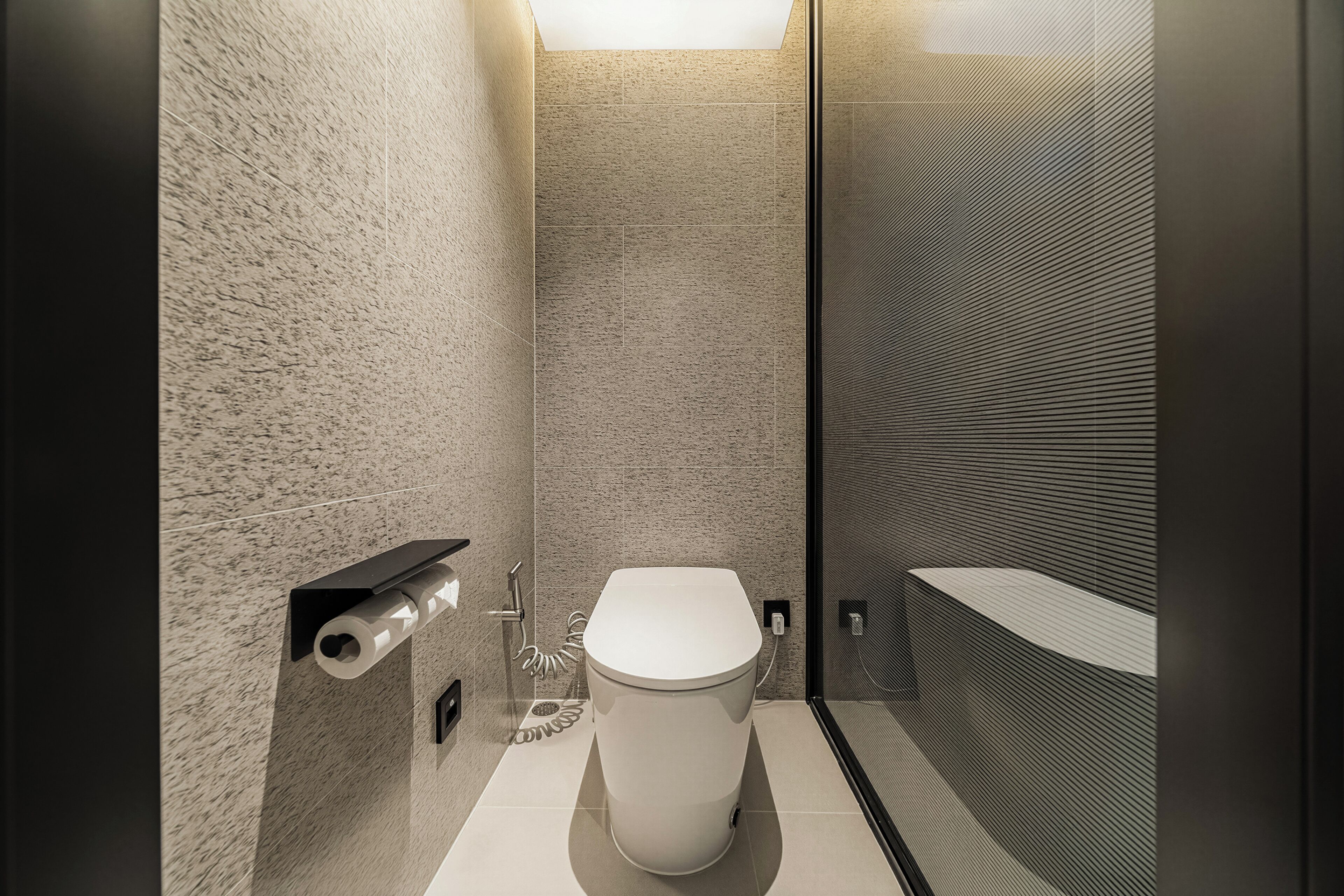 A modern bathroom with a toilet, a shower area, and a towel rack.