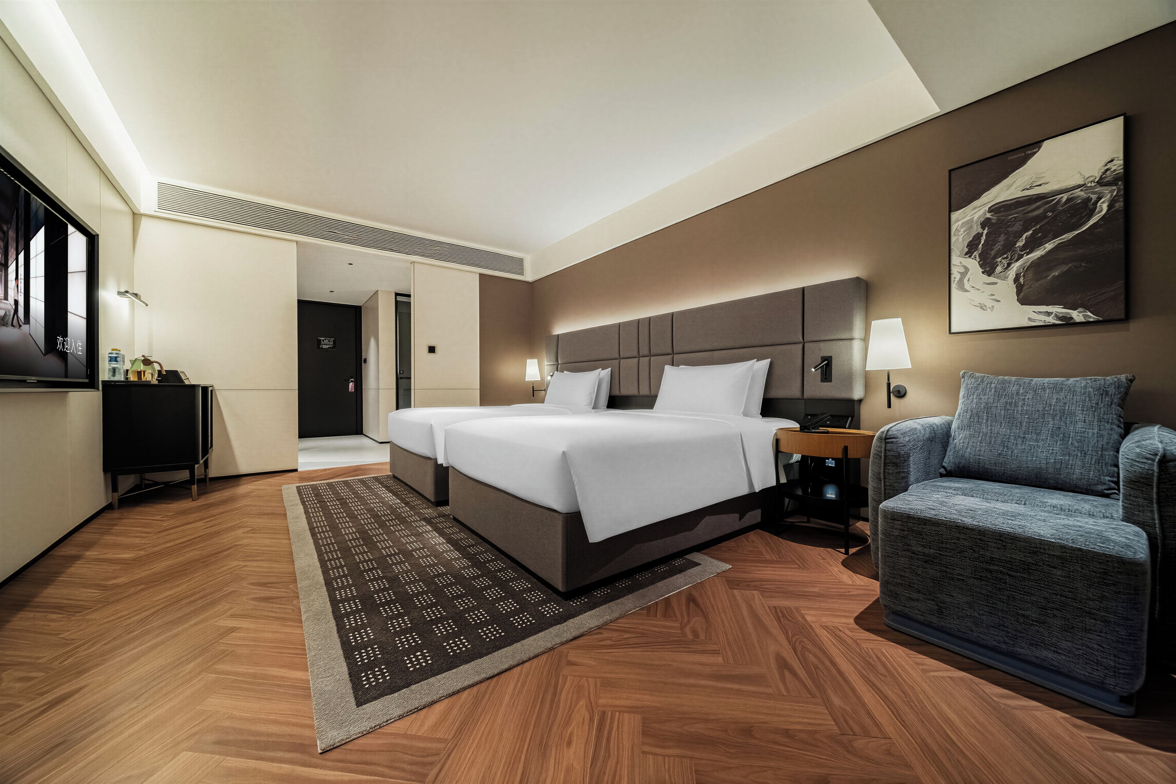 Habitación de hotel con una cama grande, zona de estar, escritorio y televisor.