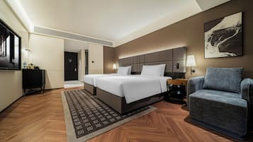 Habitación de hotel con una cama grande, zona de estar, escritorio y televisor.