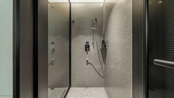 A modern shower area with a textured wall, a handheld showerhead, and a wall-mounted faucet.