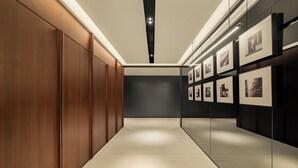 A hallway with wooden paneling, a tiled floor, and framed pictures on the walls.