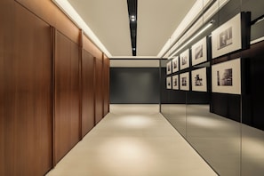A hallway with wooden paneling, a tiled floor, and framed pictures on the walls.