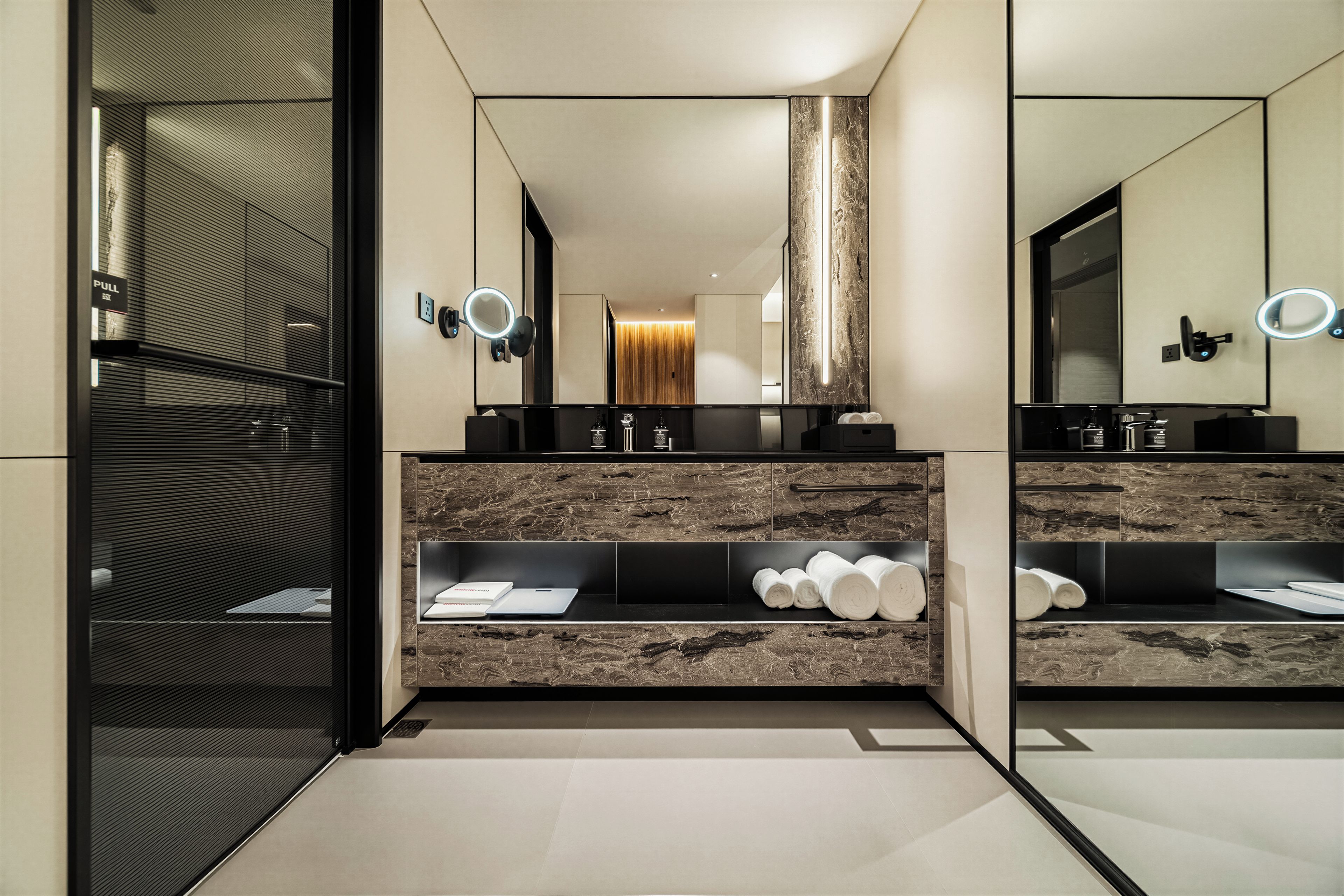 A modern bathroom with a large mirror, two sinks, and a vanity with a marble countertop.