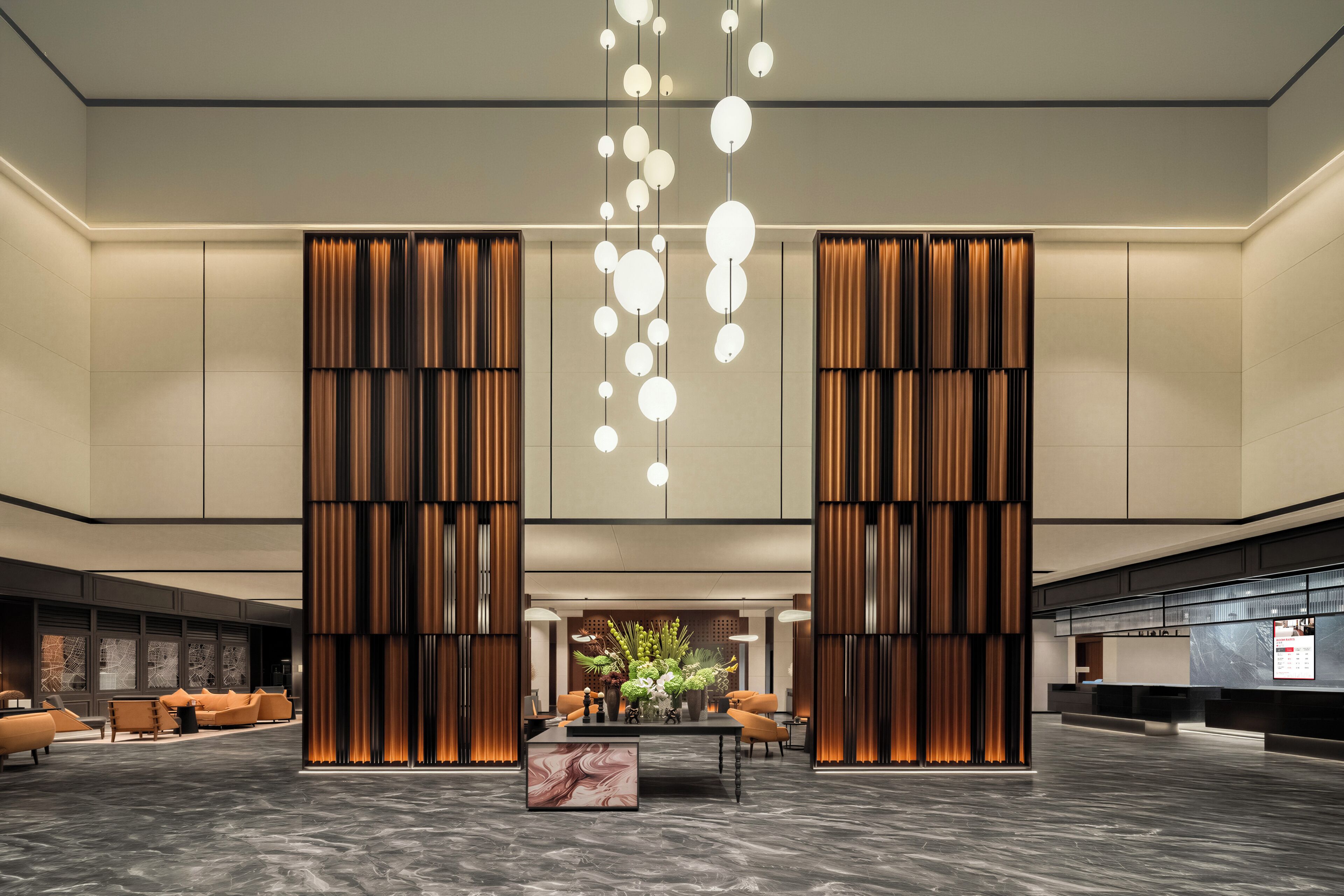 A spacious lobby with a marble floor, a central seating area with sofas, and a modern chandelier.