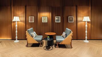 A hotel lobby with two leather armchairs, a small round table, and two floor lamps.