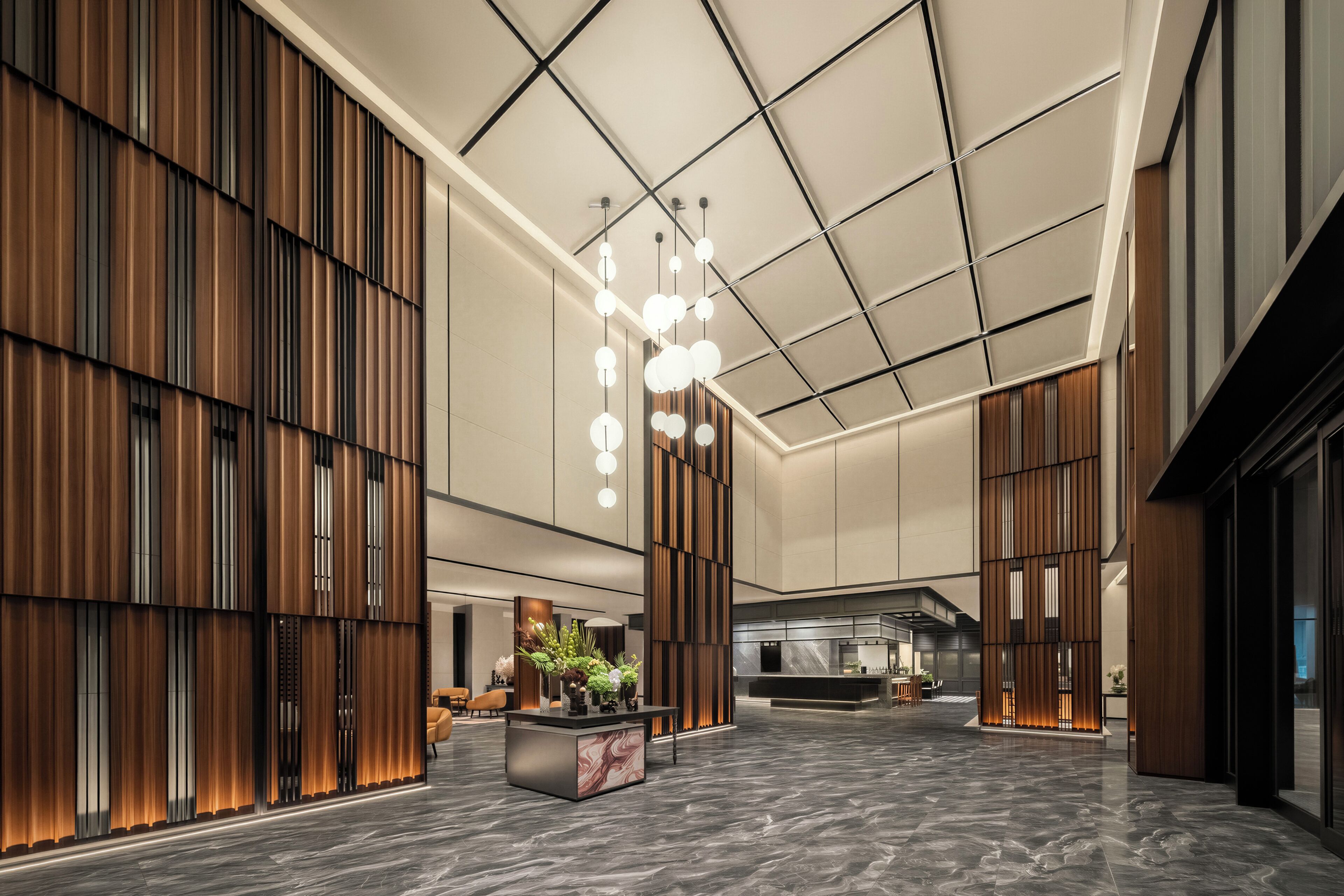 A spacious lobby with a reception desk, seating area, and a modern ceiling design.