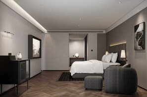 Ein modernes Hotelzimmer mit Bett, Nachttisch, Lampe und einem grauen Sessel.