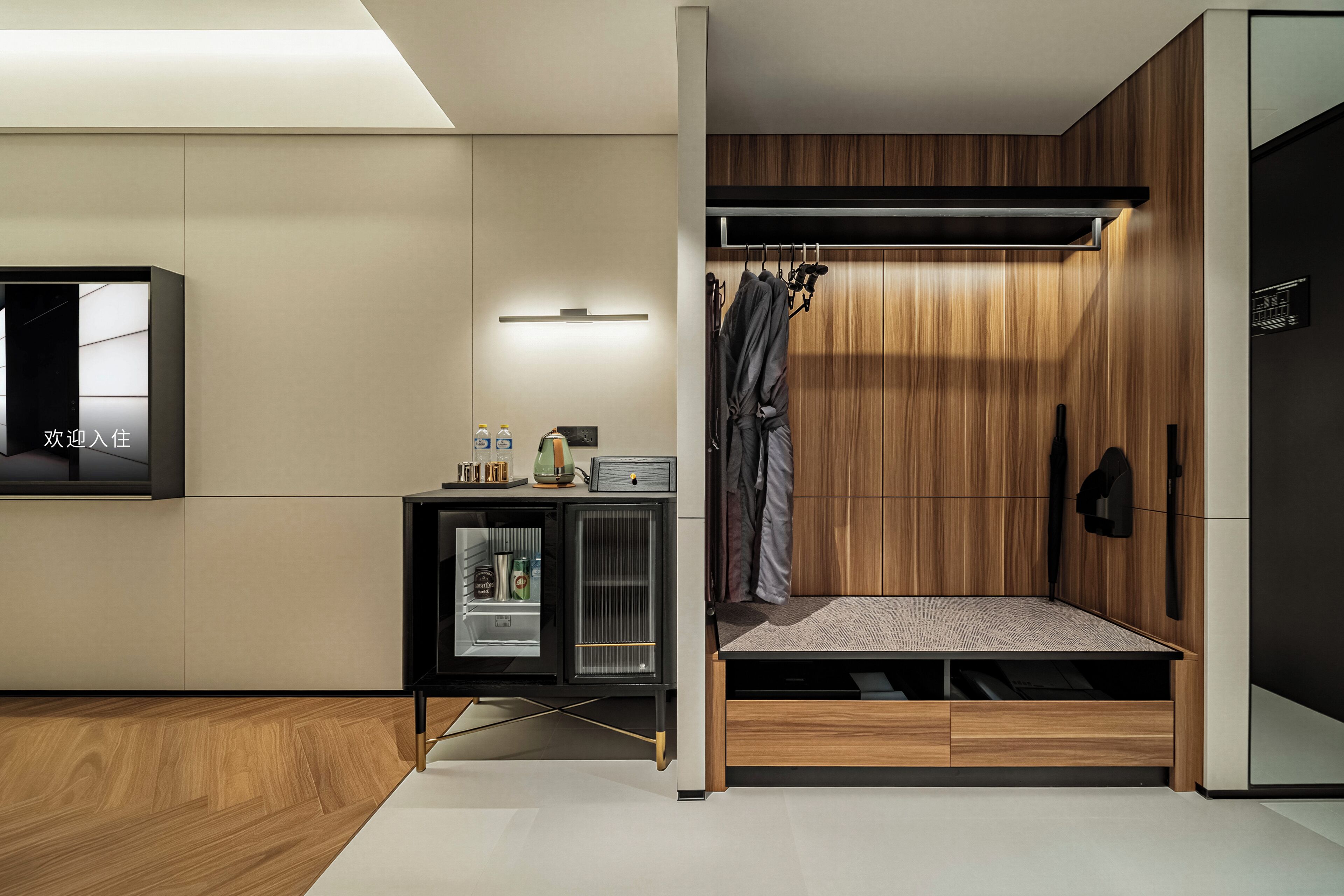 A compact room with a bed, a small kitchenette, a television, and a wardrobe.