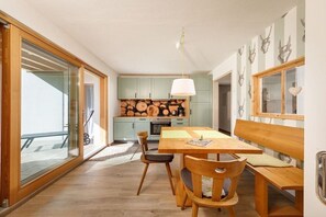 Eine moderne Küche mit hellgrünen Schränken, einem Holztisch und einer Bank.