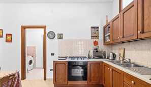 A compact kitchen with wooden cabinets, a gas stove, a microwave, and a built-in oven.