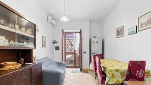 A compact living space with a dining area, a sofa, a cabinet with glass doors, and a refrigerator.