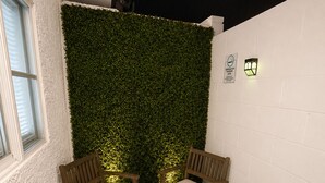 A corner seating area with two wooden chairs and a small table, a green wall, and a white wall with a light fixture. - Cozy 1-bedroom apartment in charming Las Vegas with AC (Las Vegas)
