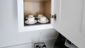 A kitchen cabinet with white interior, containing two wine glasses and four white cups on shelves. - Cozy 1-bedroom apartment in charming Las Vegas with AC (Las Vegas)