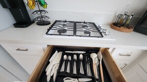 A kitchen with a gas stove, a drawer with utensils, and a coffee machine. - Cozy 1-bedroom apartment in charming Las Vegas with AC (Las Vegas)