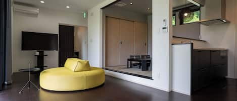 Una sala de estar moderna con un sofá amarillo, un televisor de pantalla plana y un comedor con mesa y sillas.