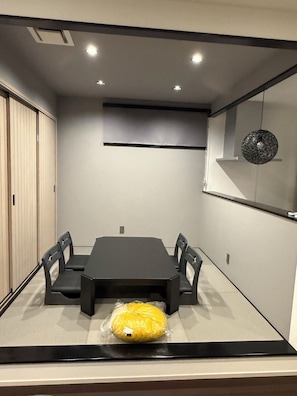 A conference room with a dark table, chairs, a projector screen, and a hanging light fixture. - Yogo Lakeside Villa Kagamigaoka (Nagahama)