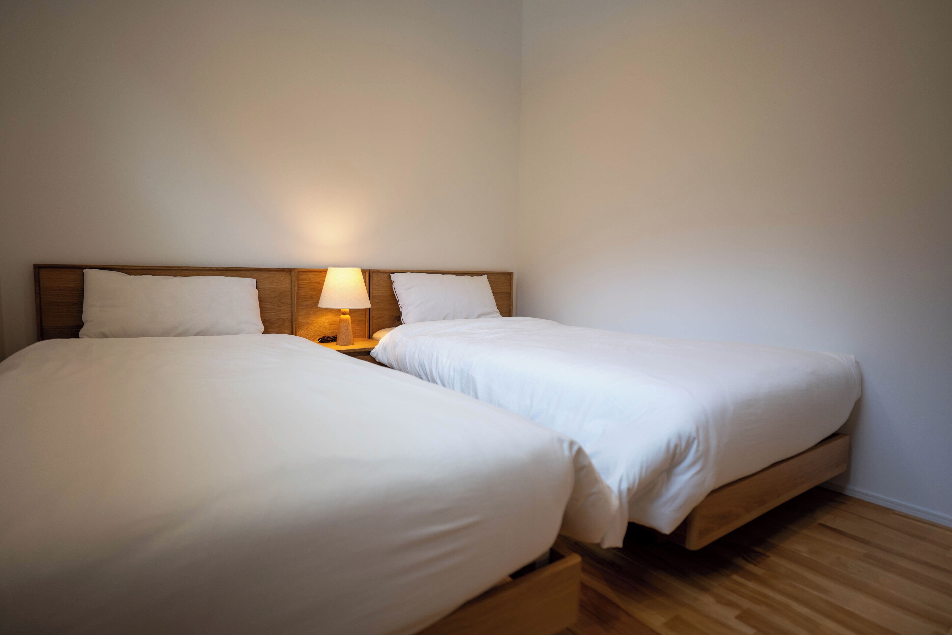 A double bed with a wooden headboard and a bedside table with a lamp.