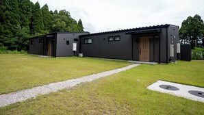 A modern building with a flat roof, a gravel pathway leading to the entrance, and a grassy area in front.