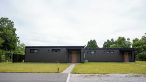 Un bâtiment moderne doté d’un toit plat, de deux portes apparentes et d’une allée pavée.