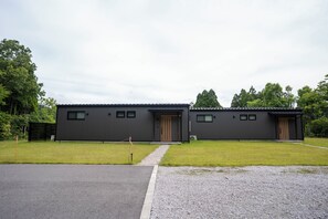 En modern byggnad med ett platt tak, två synliga dörrar och en asfalterad uppfart.